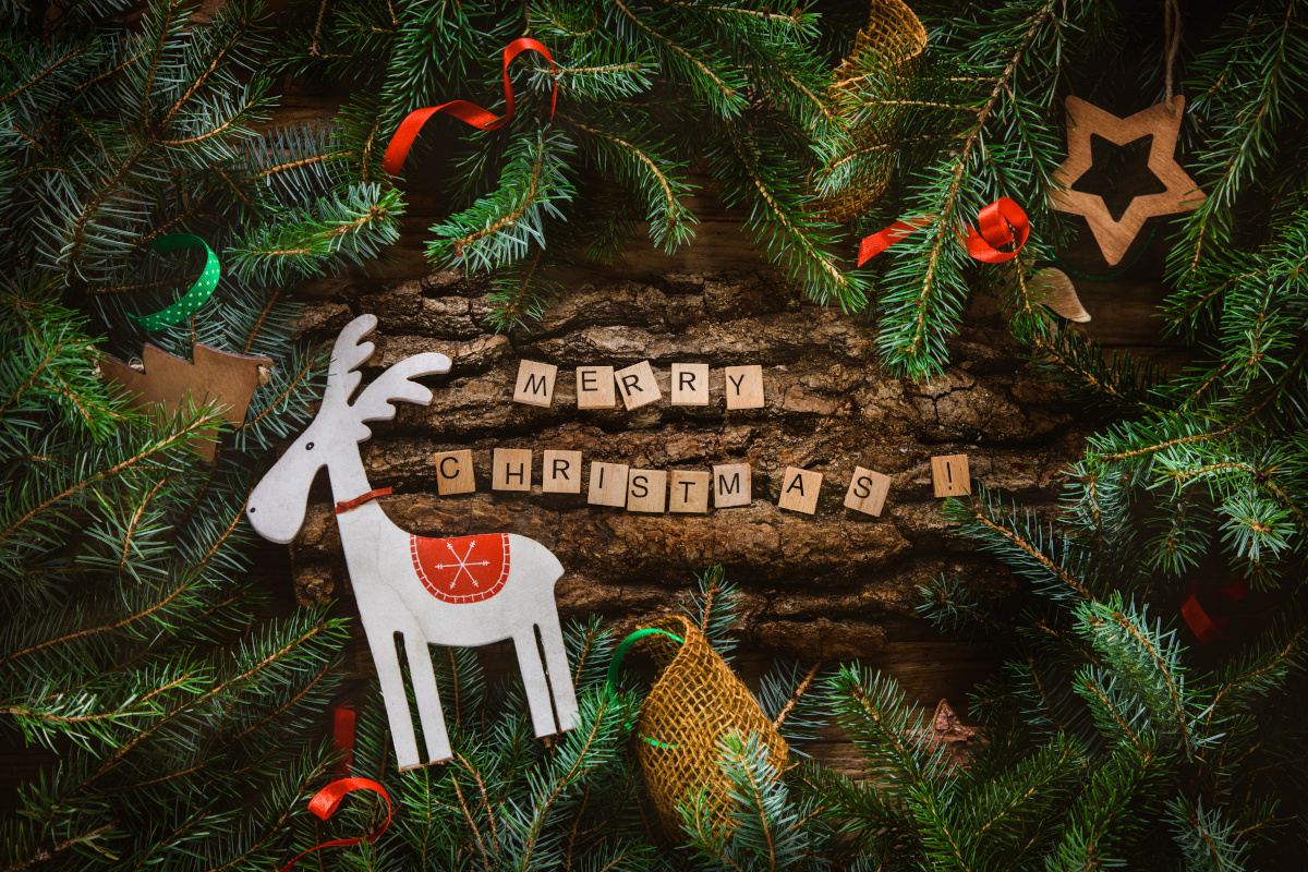 Reindeer Ornament and 'Merry Christmas' on Tree Sourrounded by Pine Needles and Other Ornaments