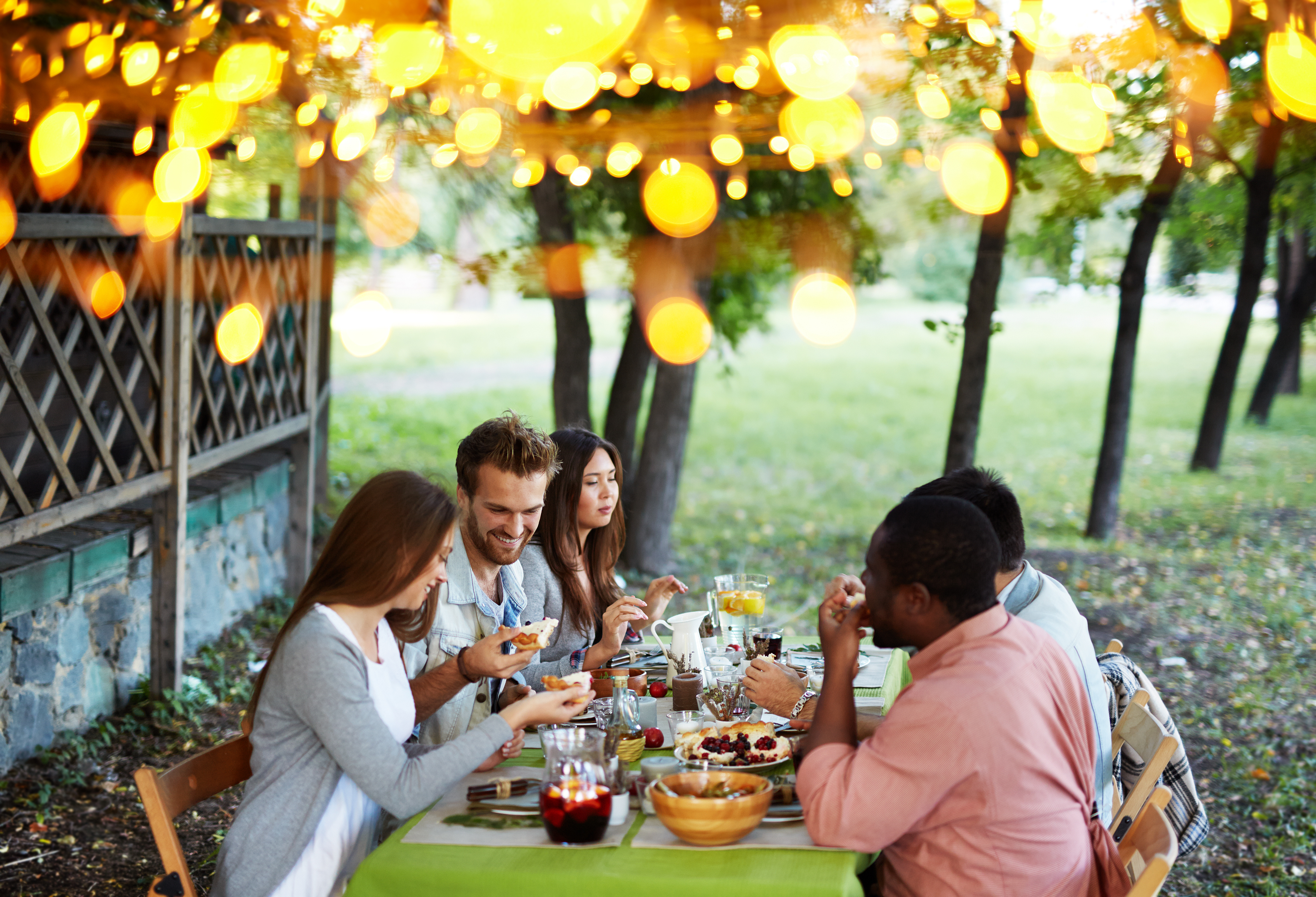 Group of Young Friends Seated Around Thanksgiving Table for Dinner Outdoors
