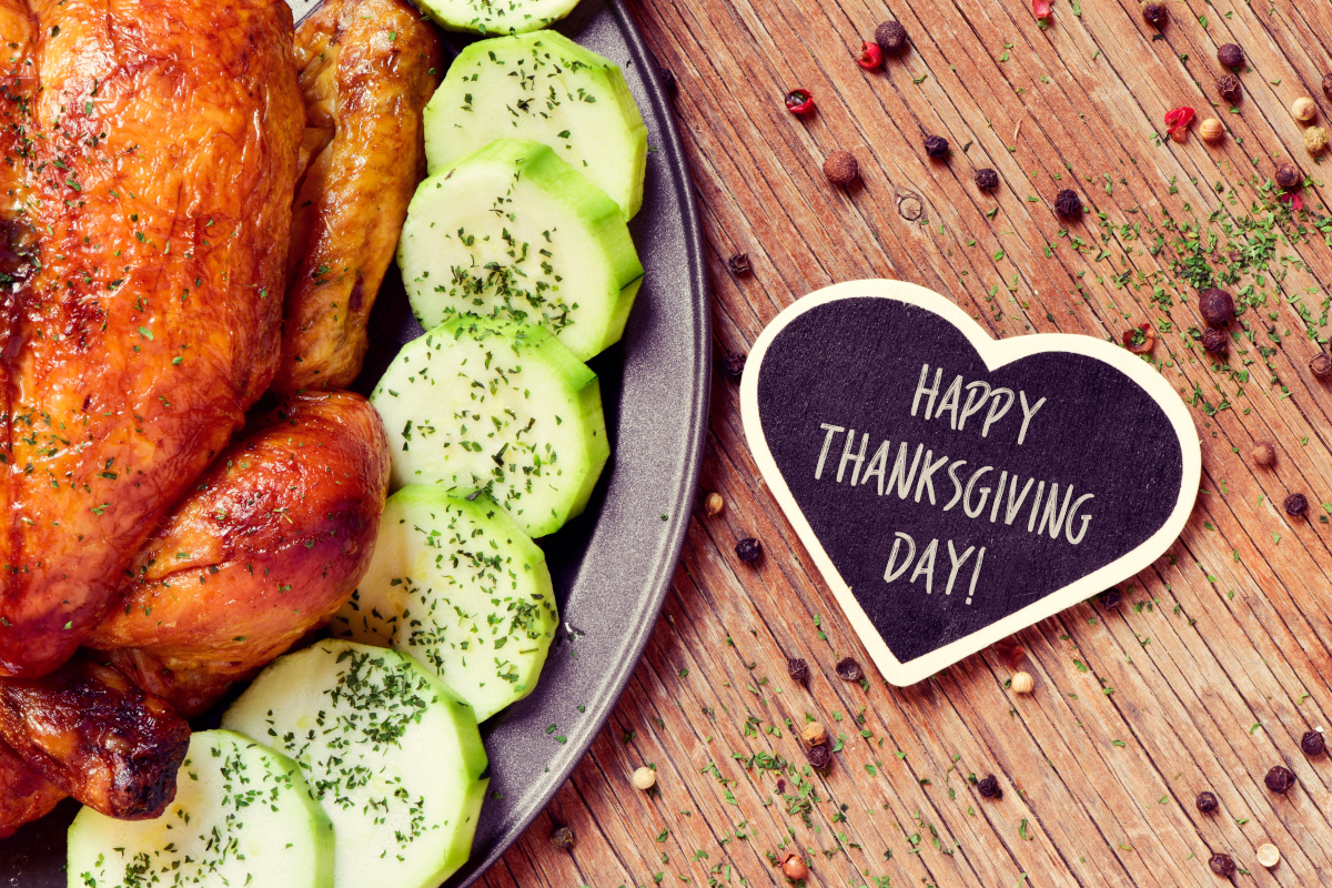 'Happy Thanksgiving Day!' on Heart Shaped Card Next to Traditional Roast Turkey on Wooden Table